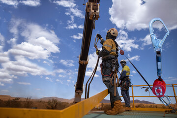Safety workplace trained competent using an inertia reel absorbing hook fall arrest device clipping...