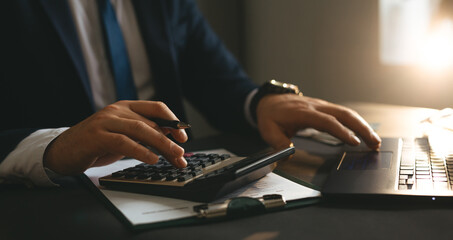 Businessman using calculator and laptop for calculate bills Finances, savings and economy concept. Tax and accounting.	
