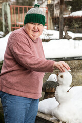 mentally handicapped or disabled woman is forming a snowman outdoors