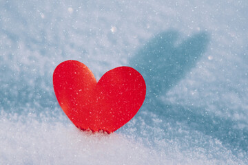 Lonely valentine. Red heart in cold, frosty morning snow. Valentine's Day greeting card. A symbol of love and romantic relationships. Congratulations on holiday of February 14. Copy space for text