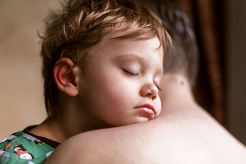 close up view of cute sleeping baby boy putting his head on dad's shoulder. Image with selective...