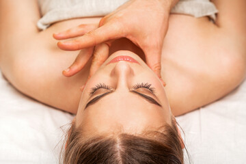 Chin or neck massage of a young woman by the hand of a male massage therapist in a spa salon