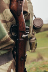 A man in a soldier's camouflage uniform with a rifle carbine on his shoulder during a...