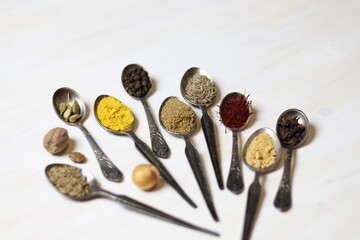 Hawaij or hawayij, is a variety of Yemeni ground spice mixtures used  for soups and  coffee in metal spoons on white wooden table