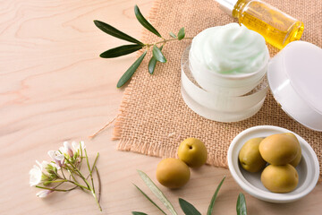 Fototapeta na wymiar Serum and olive moisturizing cream for skin on wooden top