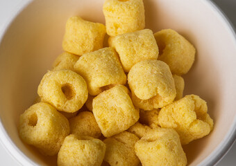 Crispy Corn rings salty snacks in bowl. Fast food or junk food snacks unhealthy concept.