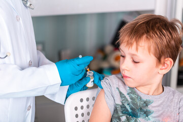 Fototapeta premium Doctor or nurse in uniform and gloves wearing face mask protective in lab making an injecion holding vaccine bottle with COVID-19 Coronovirus vaccine label