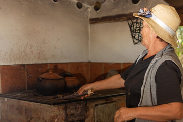 Old farmer woman igniting an old coal stove in a country house in Colombia