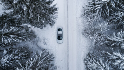 White modern car with sunroof in winter forest.  Country road going through the beautiful snow...