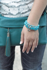 Female hand with a turquoise blazer. Hand with a bracelet made of blue stones. Marine style accessory.