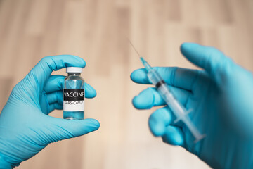 Doctor hands in protective gloves hold vaccive and syringe