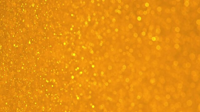 Glittering Golden Particles With Bokeh. Yellow gold defocused circular facula. Natural Floating Organic Abstract Particles. Background. Christmas and Happy new year. Slow motion.