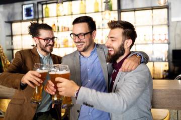 Young businessmen are drinking beer, talking and smiling while resting at the pub