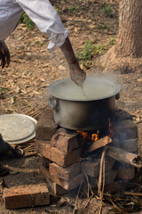 An aluminum utensil on a temporarily made fire oven by bricks.