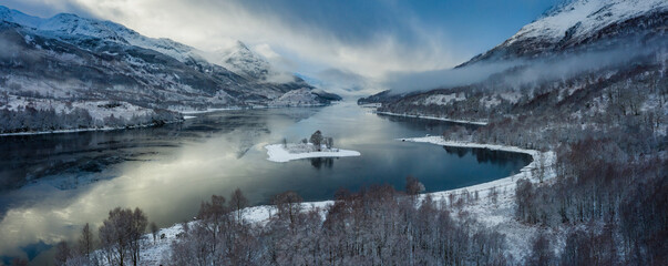 aerial view of a remote scottish island on a sea loch in the argyll region of the highlands of scotland during a snow storm in winter © Andy Morehouse