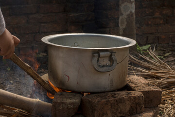 An aluminum utensil on a temporarily made fire oven by bricks.