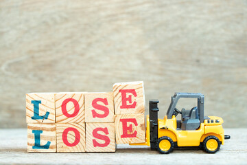 Toy forklift hold letter block e to complete word lose lose on wood background