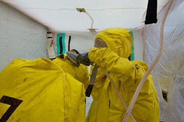 Hazmat team of firefighters to work in a harmful toxic environment in protective clothing during decontamination using a special shower
