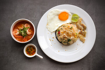 Close up Gourami Fried Rice Served with Tom Yum Kung And chili fish sauce Placed on a black marble table seen from above.