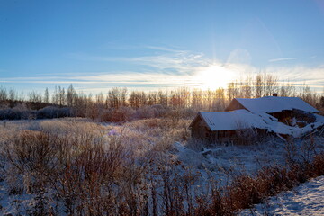 Old hut in a snowy field near the forest