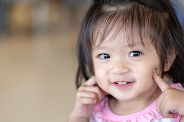 Happy Little asian girl child showing front teeth with big smile and laughing