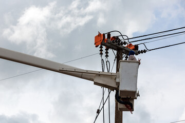 electricians repairing wire of the power line on electric power pole
