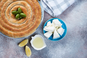 Spanakopita or greek spiral pie made of filo dough, top view over beige stone background with copyspace, horizontal shot