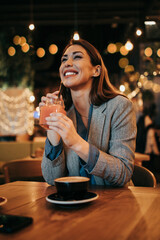 Beautiful young adult woman sitting in a nice restaurant or coffee bar and enjoying in fresh good coffee drink.