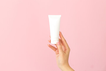 Woman holding cream tube and applying moisturizer lotion