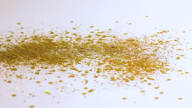 gold sequins and rhinestones pour from above and shimmer beautifully on a white background close-up, festive background
