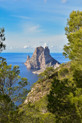 Ibiza, Spain - January 06, 2021: View of the mysterious island of Es Vedra into trees