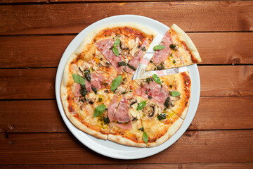 pizza with ham, mushrooms and cheese on the plate