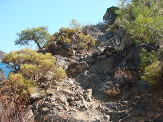 Landscape of a mountain path that rises on the slope of a mountain range through numerous stone obstacles.