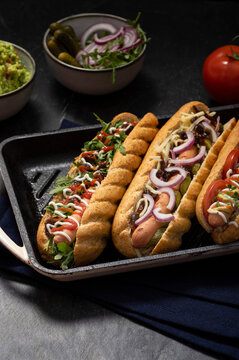 Gourmet dirty hot dog sandwich with various garnish on black slate background. Healthy option of fast food.