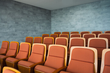 Fototapeta premium Row of brown theatre seats and marble wall in auditorium