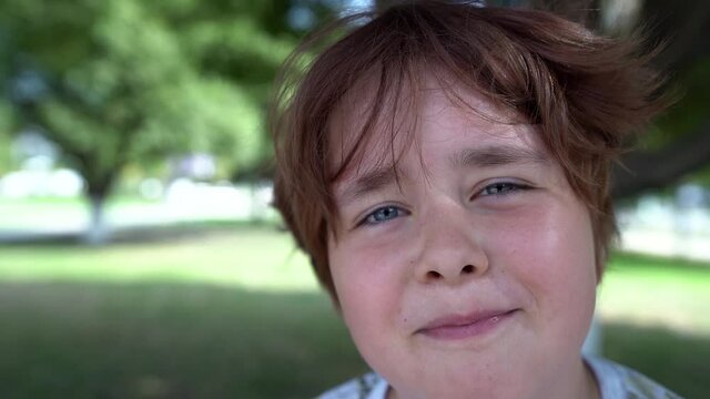 close-up of a child's face with short hair, plump cheeks and a smile against a background of green trees. wide angle lens