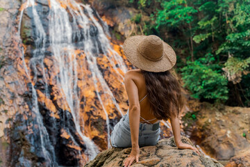A beautiful girl is resting in the jungle near a waterfall. Na Muang Waterfall at Samui Tourist destination Thailand Koh Samui. 