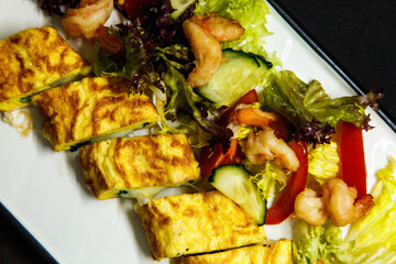 Roll of omelette and fresh salad on a black background