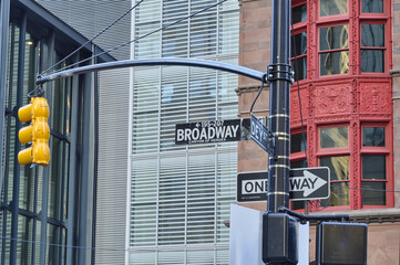 Lower Manhattan, New York, USA 
Green street signs Broadway and Dey St. on buildings facade background. Close-up of traffic lights, One Way street sign. 