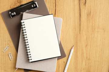 Stack of clipboard, notebook, notepad and office supplies on wooden table. Top view, flat lay.