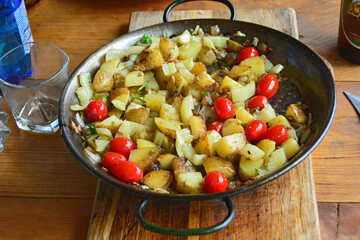 Fried potatoes with onion and mini-tomatoes.