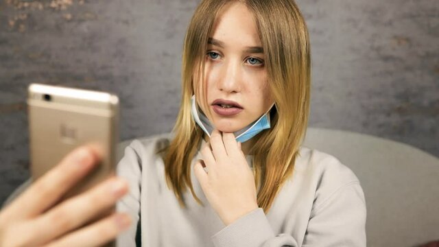 Frustated young blonde woman feeling upset using smartphone's face unlock feature wearing face mask