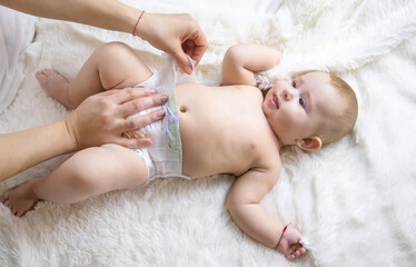The mother is changing the baby diaper. Selective focus.