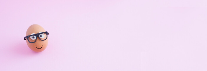 creative egg with glasses on pink background, happy easter concept, banner