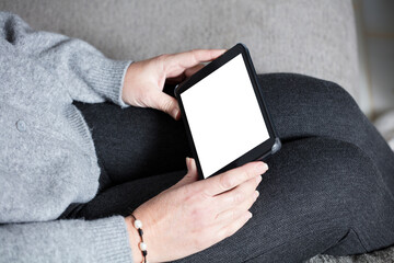 woman with gray clothes and tablet in hand (white screen) sitting in armchair