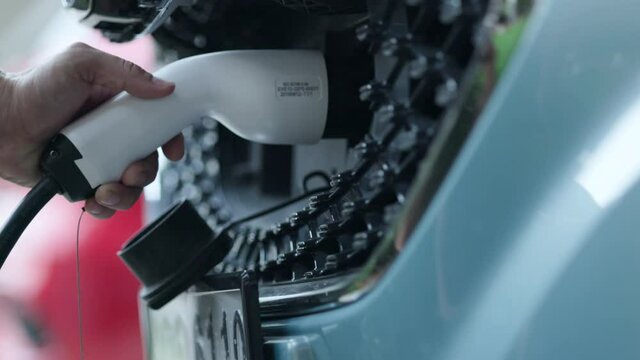Close-up of charging hand to power the electric Car. Automotive technology of the future. Save energy And protect the environment. Charging pump at home