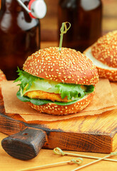 Delicious homemade burger with chicken, herbs, cheese, tomatoes and pineapples on a white bun with sesame seeds. Hawaiian-style burgers. Selective Focus