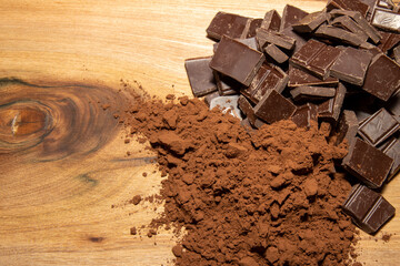 Chocolate pieces and coco powder on a wooden background, cooking ingredient concept