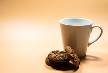 Close up white mug of milk and pile of dark chocolate chip cookies