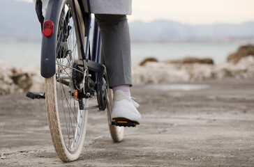 Naklejka premium partial view of bicycle with woman, gray clothes, beach in background
